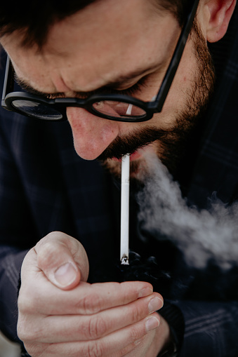 Businessman lighting up a cigarette after a workday.