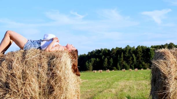 istock young female lies on a haystack and throws his hat. Rural area. freedom concept 1307331260