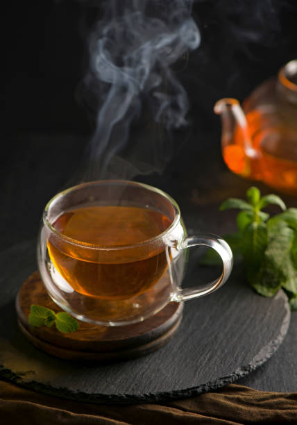 istock Tea concept, teapot with tea surrounded on wood background, tea ceremony, green tea in a transparent cup 1307332290