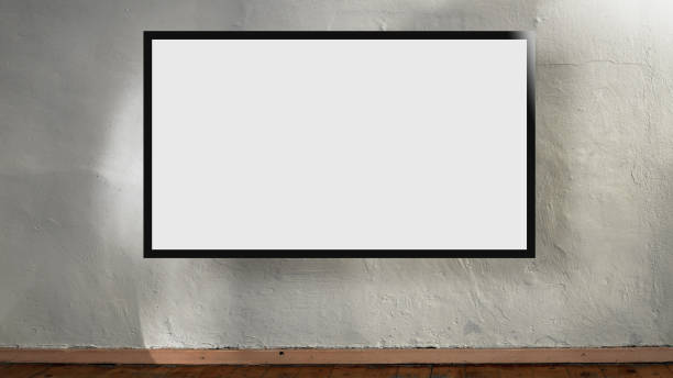 istock Wide white empty screen in black frame hanging on aged concrete wall. 1307334247
