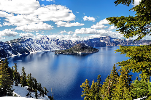 The location is Crater Lake National Park, Oregon, United States. This photo was taken just before the start of summer, when the high altitudes of the crater rim, and heavy snowfall of the cascade mountains from the previous winter, leaves many feet of snow remaining.