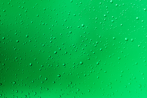 Waterdrops on a glass pane with green background