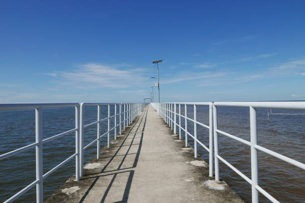 istock Perspective view of jetty with LED street light with solar cell on clear blue sky. 1307336048