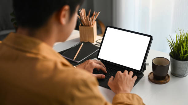 istock Over shoulder closeup view of young man working on computer tablet. 1307338268