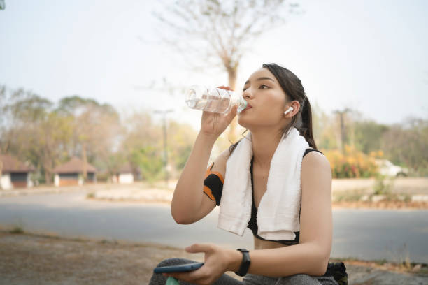 istock Young female jogger drinking fresh water from plastic bottle after running on the park. 1307338317