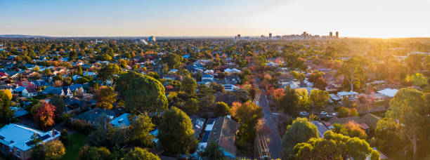 Aerial panoramic view of multi-coloured autumn Adelaide sunset Aerial panoramic view of backlit multi-coloured autumn Adelaide sunset with the city centre skyline in silhouette: sunlight highlights colours in landscape: clear sky adelaide stock pictures, royalty-free photos & images