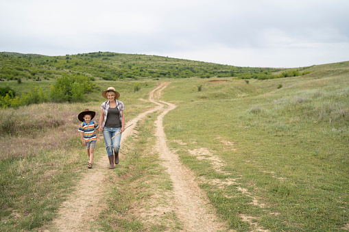 Mother and son walking hand in hand on a country road