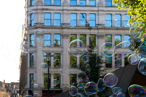 White building in downtown district in London with mirror windows through soap sud bubbles flying around