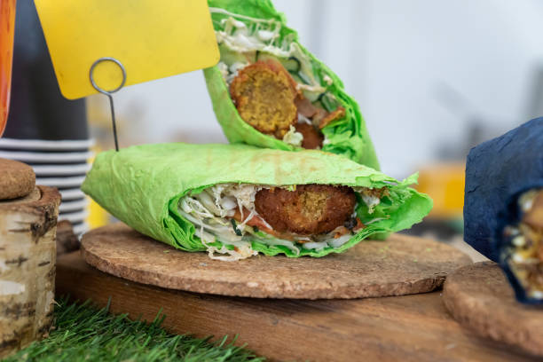 Falafel sandwich rolled in flat green bread. Vegan sandwich in lavash bread with vegetables and deep-fried ball or patty-shaped fritter made from ground chickpeas, fava beans, or both.