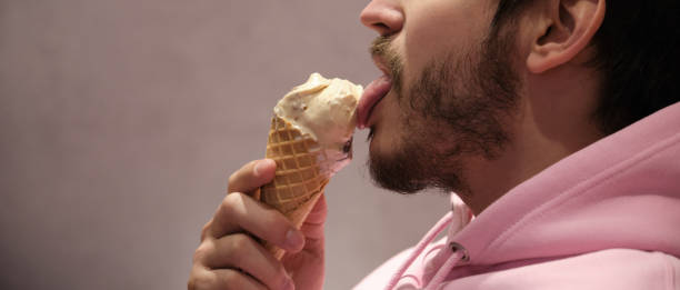 istock Unrecognizable man licking ice cream cone. Panoramic photo banner. 1307347371