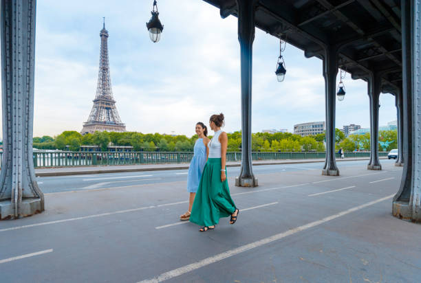 Two young women strolling down the bicycle lane on the bridge Two young women walking down the bicycle lane on the bridge under the viaduct paris fashion stock pictures, royalty-free photos & images