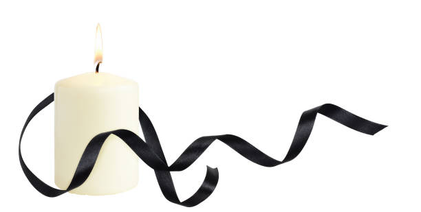 istock Waved black silk ribbon and burning candle isolated on white 1307349510