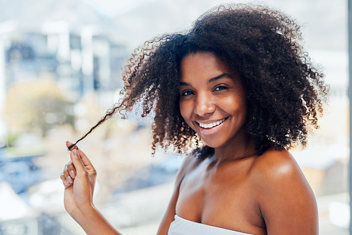 Shot of a young woman taking care of her natural hair