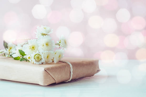 istock White chrysanthemums and a gift box on a white wooden background. Spring composition of a gift with bokeh. 1307350892