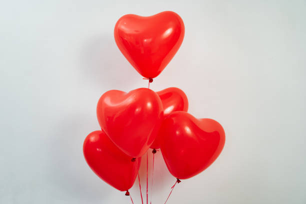 istock A heart shaped red balloons on strings against a white wall. 1307352378