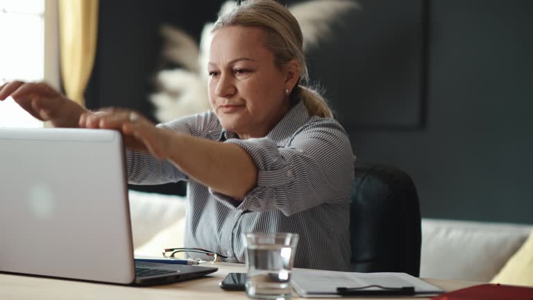 Mature disappointed woman gets upset about losing her job online. Nervous person worried about finances. An elderly woman under stress closes her laptop