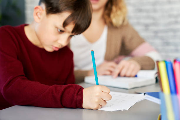 istock Close up of schoolboy doing homework at home with mom 1307354505