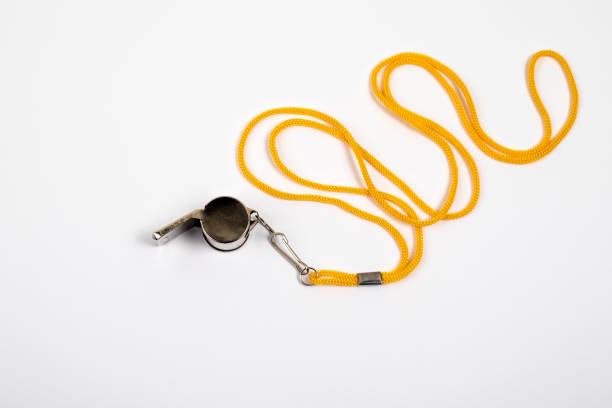 silbato de metal con un cordón amarillo sobre un fondo blanco - silbar fotografías e imágenes de stock