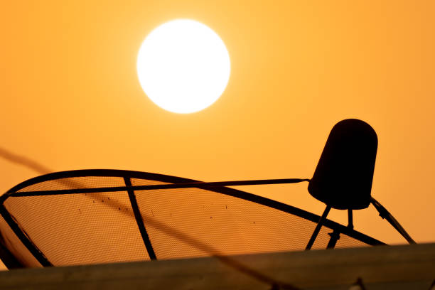 Satellite technology dish receiver on sunrise and golden sky background, blurred roof forground on light ray of sunny