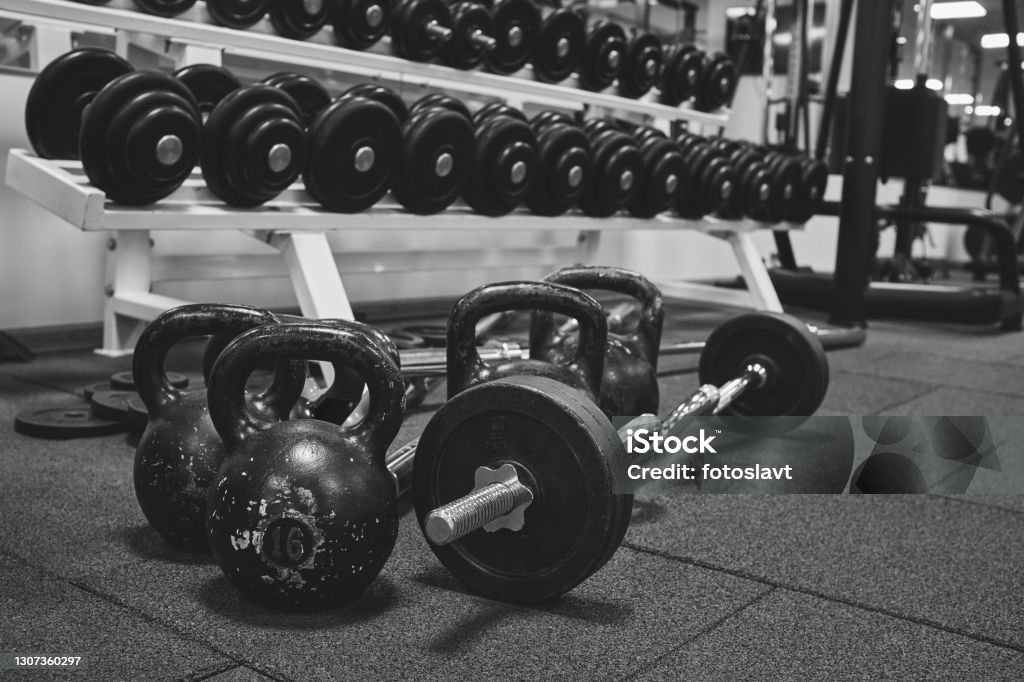 Dumbbells and kettlebells on a floor. Bodybuilding equipment. Fitness or bodybuilding concept background. black and white photography Gym Stock Photo