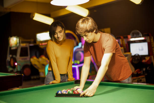 istock Couple in billiard room. Man preparing balls for game. 1307362889