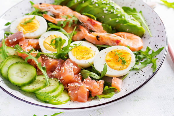 istock Ketogenic diet breakfast. Salt salmon salad with boiled shrimps, prawns, cucumbers, arugula, eggs and avocado. Keto, paleo lunch. 1307363558