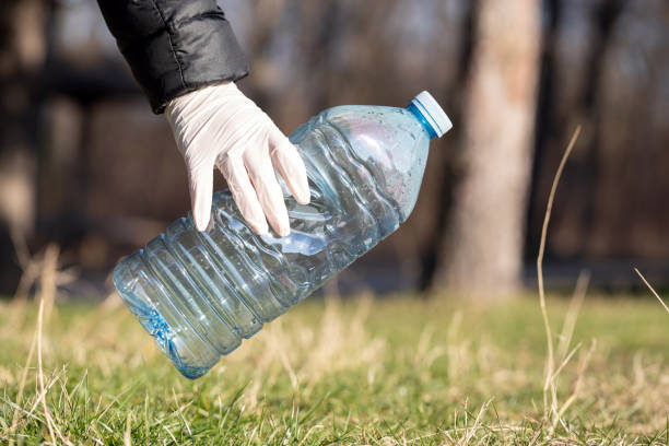 Picking up plastic bottle from ground for recycling