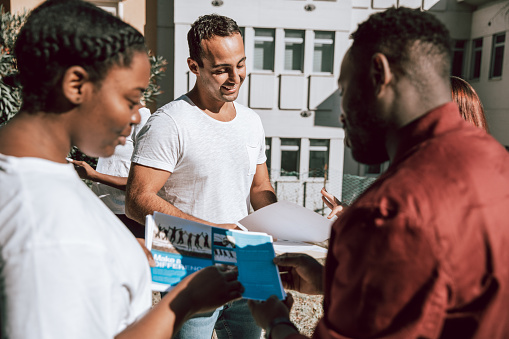 Grupo multicultural de jóvenes voluntarios distribuyen volantes y folletos en la calle photo