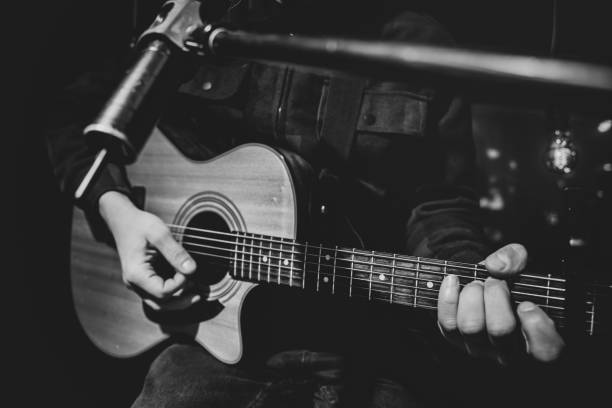 nahaufnahme spielt ein mann eine akustische gitarre in einem dunklen raum. - bass guitar stock-fotos und bilder