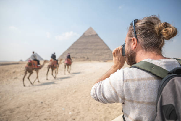 카이로에서 피라미드와 낙타의 사진을 찍는 남성 관광객 - giza plateau 이미지 뉴스 사진 이미지