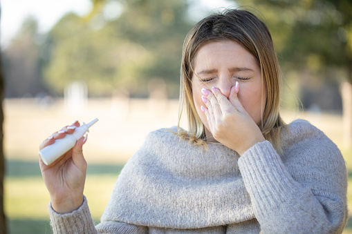 Young woman sneezing because of pollen