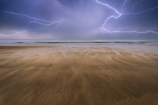 Empty beach Summer landscape with lightening storm in the distance