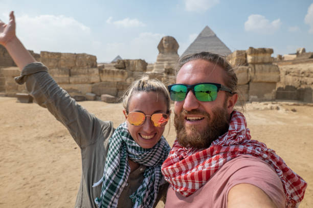 couples heureux prennent le selfie aux pyramides, egypte - tourist egypt pyramid pyramid shape photos et images de collection