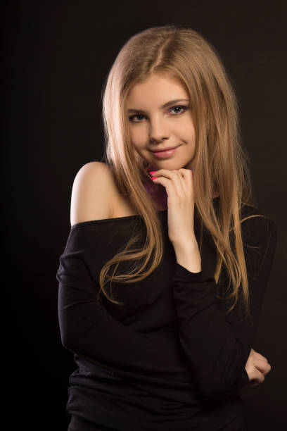 Young lady poses for this close-up portrait. She is turning her head to the side where the camera is to look over her right shoulder. She is latin, with brown eyes and hair. Her hair is brown, long and smooth. She looks like in her twenties.