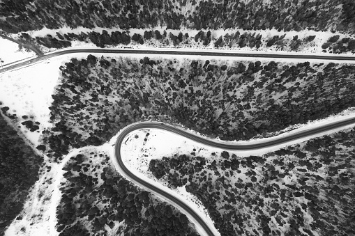 Aerial view on mountain road from drone in winter. Black and white picture