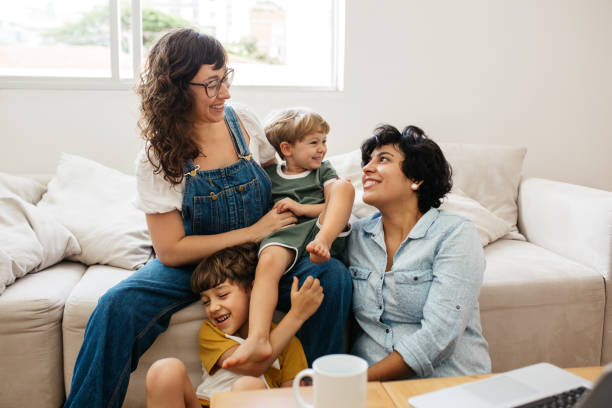 Happy LGBT family Happy lesbian couple playing with their children at home. Beautiful family of four having great time together indoors. parenting stock pictures, royalty-free photos & images