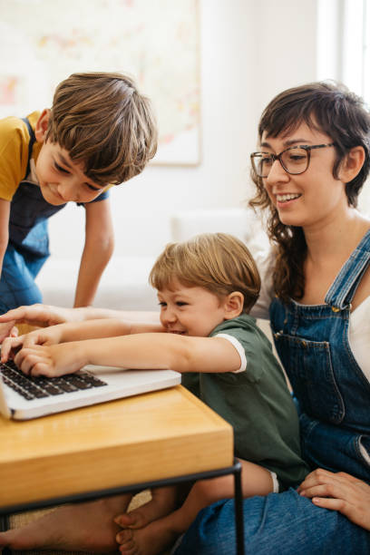 istock Boy using laptop with brother and mother at home 1307370157