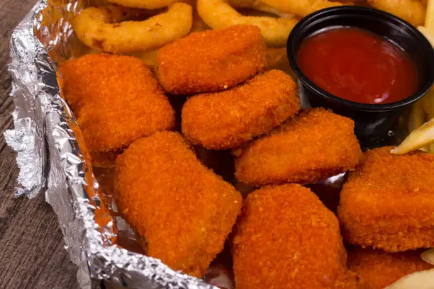 Photo of Breaded Mini Chickens Nuggets with ketchup pot. Gastronomic close-up photograph of popular foods.