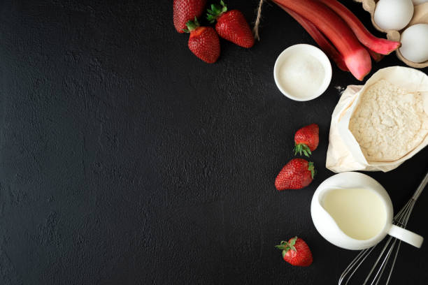 istock Baking background. Food ingredients for baking: flour, eggs, sugar, milk and berries on dark background. Flat lay. Copy space. Top view 1307372696