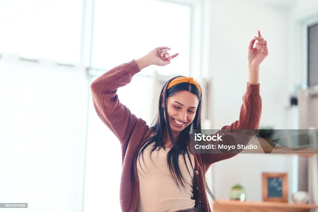 You don’t have to go outside to feel the sunshine Shot of a young woman in the living room at home Dancing Stock Photo