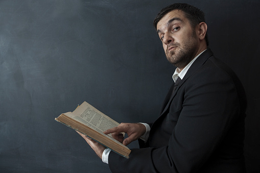 Portrait of funny businessman holding old book