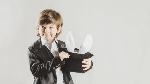 Photo of Young magician hiding a toy bunny in his top hat