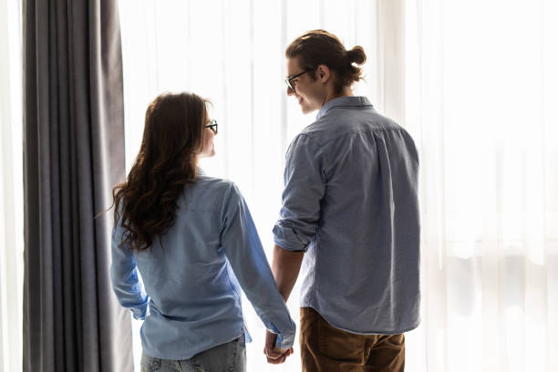 istock Back view of young couple looking out the window and hugging while having a breakfast at home 1307374815