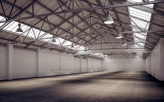 Side view of an empty large warehouse interior with white brick side walls and rough floor illuminated by natural light from ceiling lights and large roof windows. Focus on the side walls. 3D rendered image.