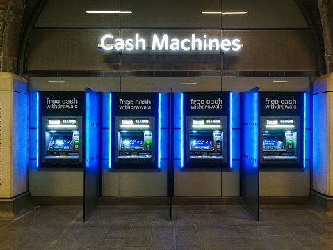 Color image depicting four cash machines (ATMs) in a row in the city.