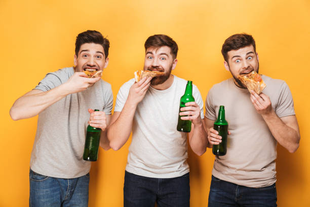 istock Three young happy men eating pizza and drinking beer 1307376796