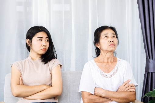 old senior Asian mother angry and ignoring her young daughter, daughter tired with annoyed mom quarrel in family