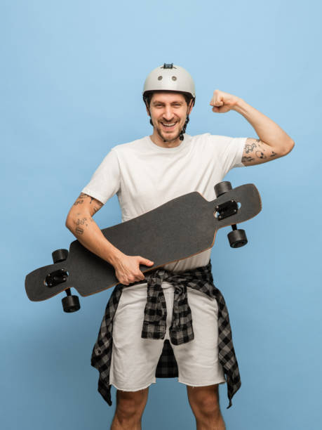 istock Happy athletic man skateboarder with longboard isolated on blue background 1307378508