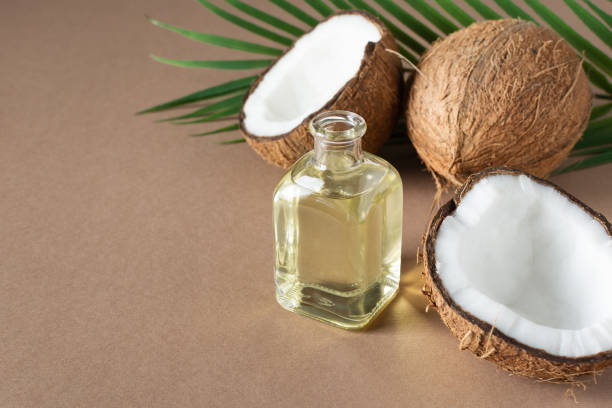 bottiglia di olio di cocco e noci di cocco fresche con foglia di palma su sfondo marrone. - alternative therapy immagine foto e immagini stock