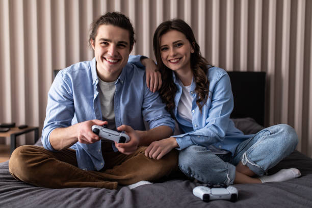 istock Happy young couple having fun playing videogames in bed 1307379999